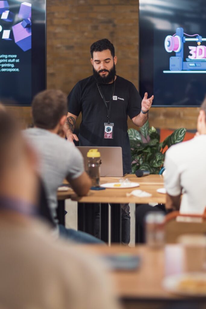 A team meeting with a presenter explaining 3D printing concepts in a modern office setting.